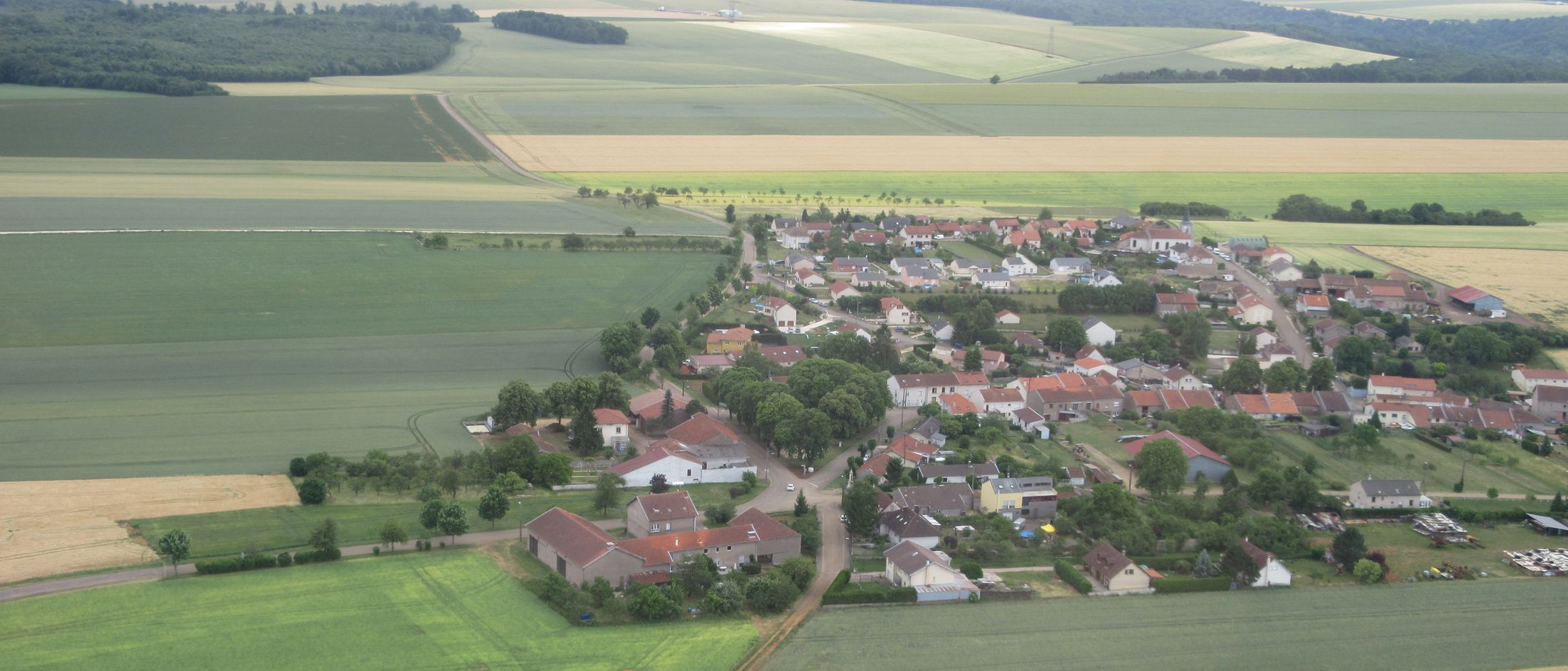 Vue aérienne du village de Mamey, entouré de champs et bordé par la forêt.