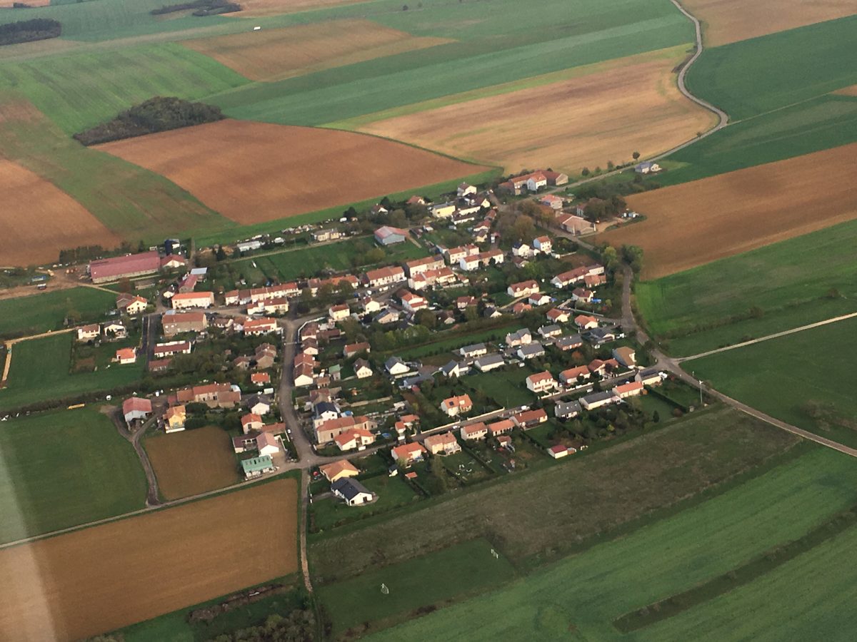 Vue aérienne rapprochée de Mamey : les maisons alignées au milieu du parcellaire agricole.